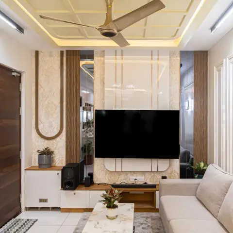 Photograph of a compact living room whose TV wall combines damask wallpaper, fluted wood, mirror strips and gold inlay lines