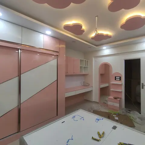 Pink and white girl's bedroom with a cloud-shaped cove-lit false ceiling, a sliding-door wardrobe and an arched dressing nook with study desk.