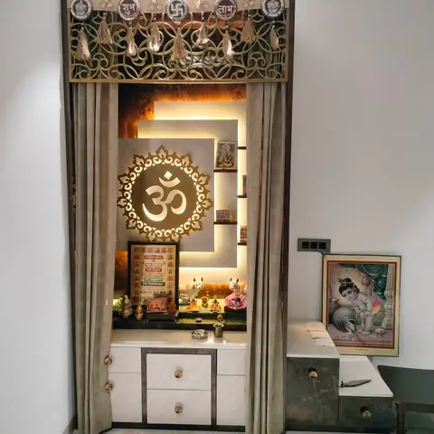 Pooja alcove framed by curtains under a brass jaali toran with Shubh-Labh medallions