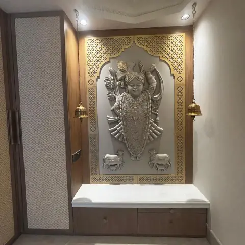 Pooja niche with a carved Shrinathji relief flanked by two cows, set inside a gold CNC-jaali mandir arch in a teak veneer surround