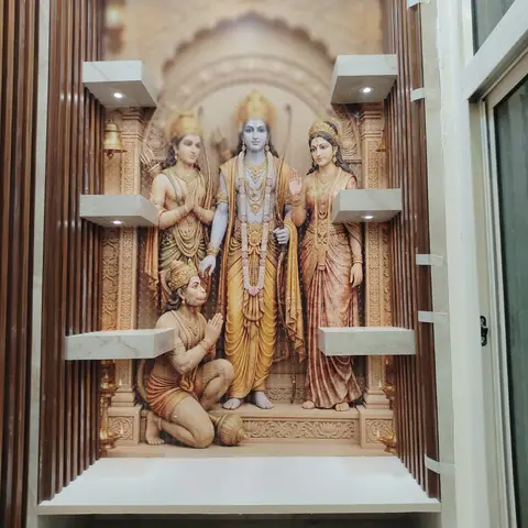 Pooja niche with a raised-relief mural of Ram Darbar and Hanuman, flanked by backlit marble ledge shelves and fluted wood panelling.