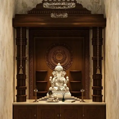 Pooja room with a carved dark wood mandir unit, turned pillar columns, a carved medallion backdrop, and a crystal chandelier overhead.