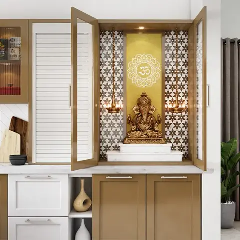 Pooja unit built into a tan-and-white kitchen-dining run, its glazed shutters folded open on a gold Om backdrop with a brass Ganesha on a white marble step