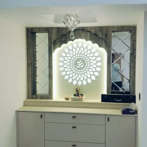 Pooja unit with a backlit Om lotus jaali panel set in a scalloped temple-arch frame, flanked by diamond-pattern mirror insets, above a storage cabinet base.