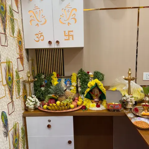 Pooja unit with a laser-cut white cabinet featuring Om and Ganesha motifs, peacock-feather wallpaper on the side wall