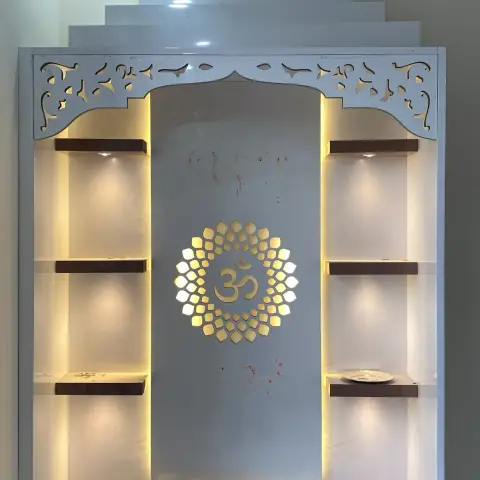 Pooja unit with a white carved jharokha-style arch, a backlit gold Om medallion on the mandir backwall, illuminated display shelves on either side