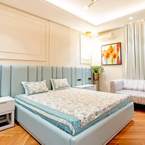 Powder-blue channel headboard running wall-to-wall under ivory raised mouldings, block-print bedding
