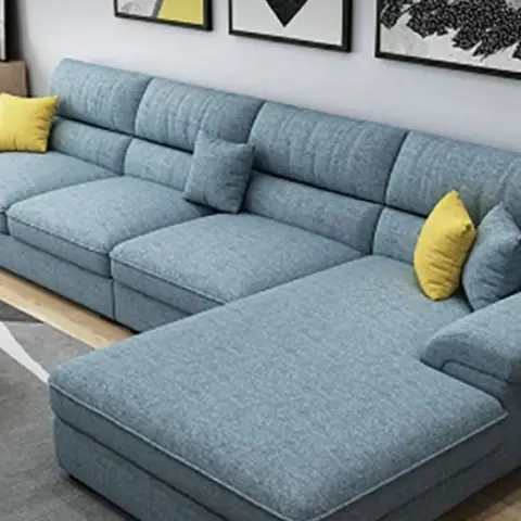 Powder-blue L-shaped fabric sofa with mustard accent cushions against a black-and-white gallery wall, with a light wood coffee table and console.