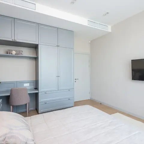 Powder-blue shaker-fronted wardrobe with an integrated desk niche and overhead cabinets fills one wall of a compact bedroom
