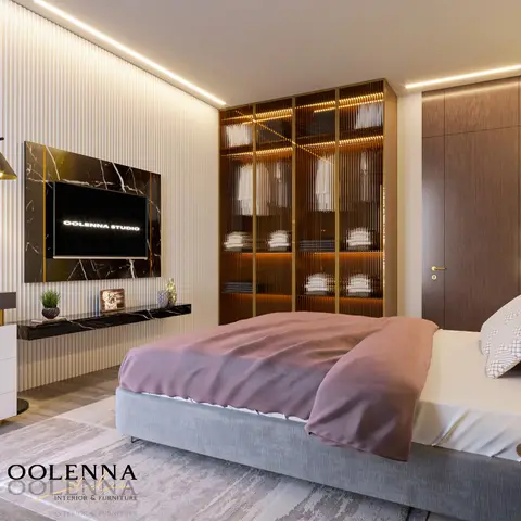 Primary bedroom with a grey upholstered bed and blush throw, a floor-to-ceiling reeded-glass wardrobe lit with warm LED strips