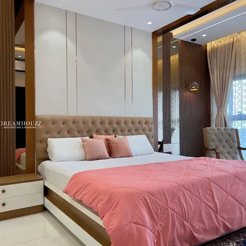 Primary bedroom with a tufted leather headboard, brass-inlaid vertical wall panelling, a fluted wood-and-mirror room divider, and sheer patterned curtains.