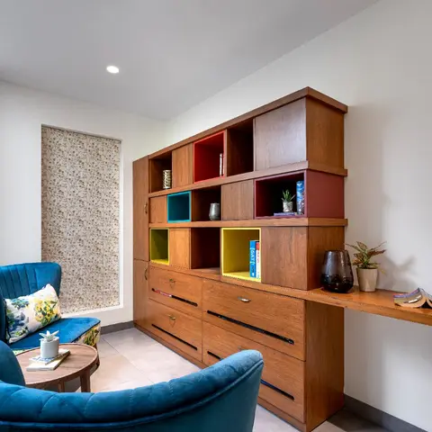 Reading nook with a mid-century wood cubby unit in red, teal and yellow accent boxes