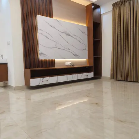 Real handover-stage living room with a fluted wood and marble-slab TV unit wall, glossy cream marble flooring, and gold curtains, still unfurnished.