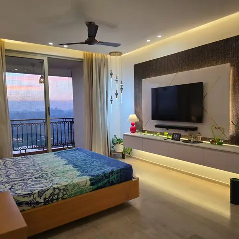 Real high-rise bedroom with a wood platform bed, a floating TV console with LED underlighting against a metallic-textured gold-lined feature wall