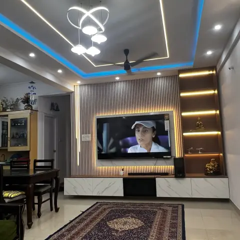 Real living room with a fluted wood TV feature wall with a backlit marble panel, a floating marble-effect TV console, lit display shelving with idols