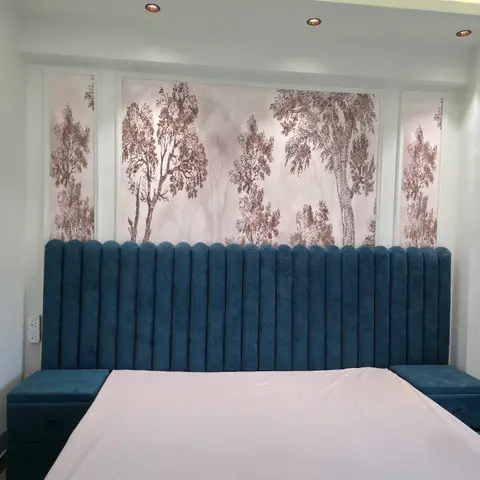 Real photo of a bedroom with a tall channel-tufted teal velvet headboard flanked by matching upholstered side benches