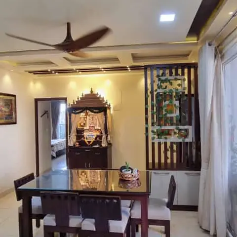 Real photo of a dining area with a dark wood table and cushioned chairs in front of a temple unit against the wall