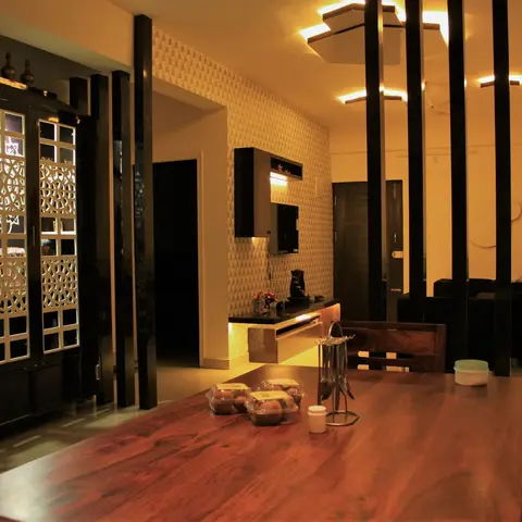 Real photo of a dining room with a solid-wood dining table in the foreground, a black jaali-fronted pooja cabinet to the left