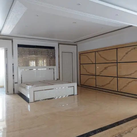 Real photo of a large bedroom mid-finishing with a black-bordered inlaid marble floor, a mirrored mother-of-pearl bed
