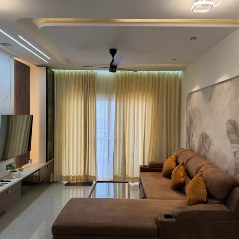 Real photo of a living room with a marble-clad TV wall, a botanical mural wallpaper behind a brown leather reclining sectional