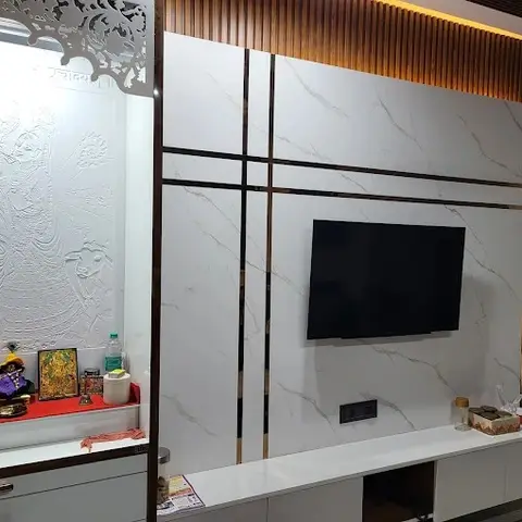 Real photo of a living room TV feature wall in book-matched marble panelling with brass inlay strips and a fluted wood border