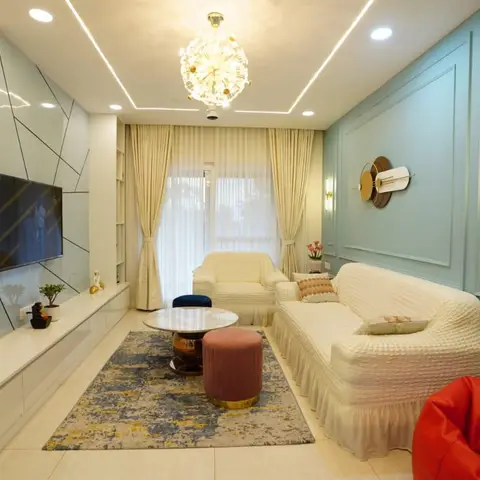 Real photo of a living room with a mint-blue moulded panel wall, brass wall sconces, a sputnik-style chandelier