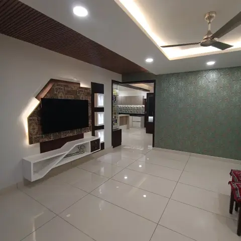 Real photo of a living room with an angular floating TV console below a backlit patterned wall panel, a teal damask-print wallpaper accent wall