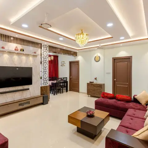 Real photo of a living room with a marble-clad TV wall framed by fluted wood trim, a multi-tier cove-lit pop ceiling with a crystal chandelier