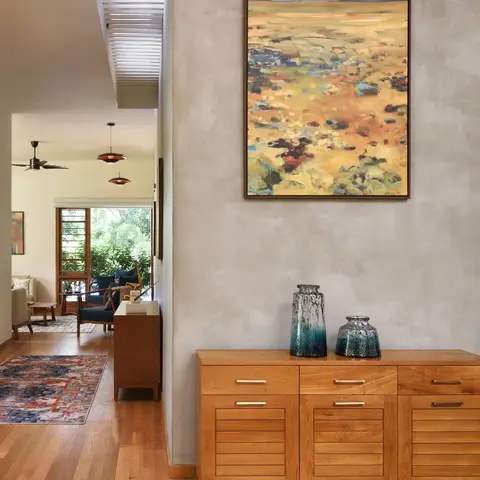 Real photo of a mid-century style entrance hallway with a wood credenza topped with ceramic vases
