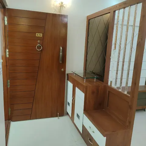 Real photo of an apartment entrance with a panelled teak main door with a brass ring handle