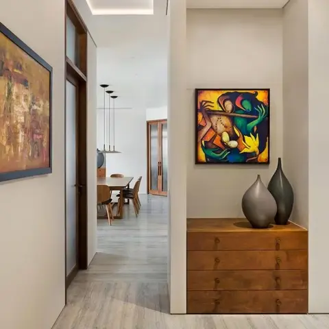 Real photo of an entrance foyer with a walnut chest-of-drawers console styled with ceramic vases beneath a bold abstract painting