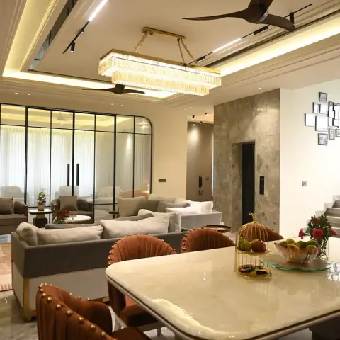 Real photo of an open-plan villa great room showing a marble dining table with rust-velvet studded chairs in the foreground