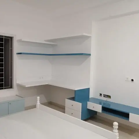 Real photo of an unstyled kids' bedroom with a white spindle-post bed, a powder-blue corner study desk with floating shelves