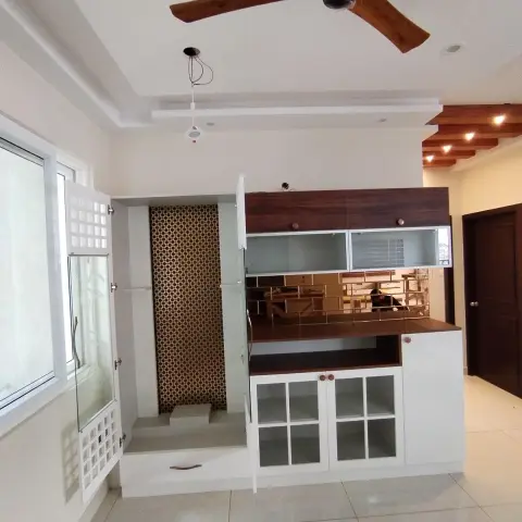 Recessed pooja unit with a gold trellis-print back panel and a stepped platform behind etched sliding glass doors