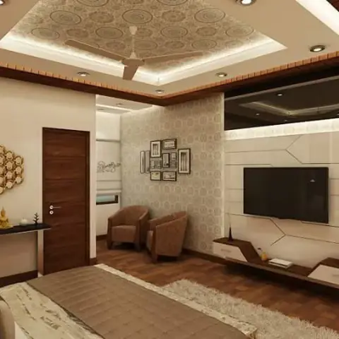 Render of a bedroom shot from the bed's foot, showing a cream TV wall cut into angular faceted panels with a stepped wooden console below