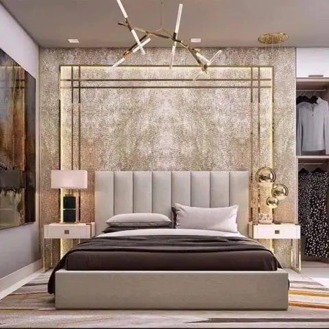 Render of a bedroom where a gold damask-textured wall is outlined by a backlit brass frame behind a pale channel headboard, with brass sphere sconces