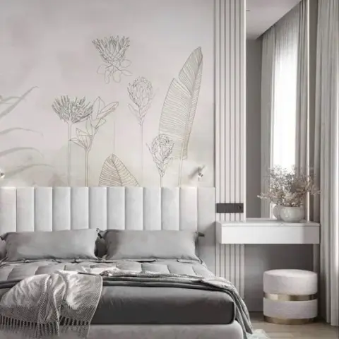 Render of a bedroom with a channel-tufted grey headboard, a botanical line-art wall mural, and a floating dressing console against fluted wall panelling.