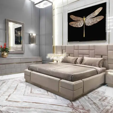 Render of a bedroom with a tufted taupe upholstered bed and panel headboard, a dragonfly art piece, and a mirrored dresser with brass trim.
