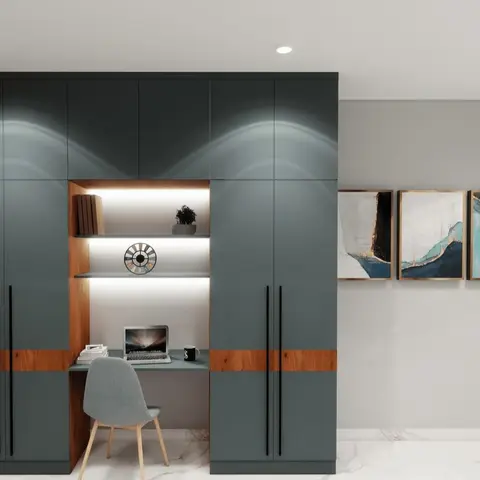Render of a built-in study nook with lit open shelving inside a dark teal-grey wardrobe wall, a laptop desk, and a grey accent chair.
