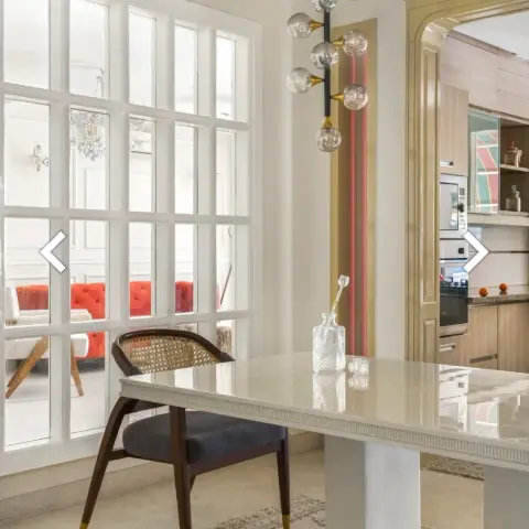 Render of a dining nook with a cane-back chair and marble-top table under a brass multi-globe pendant light