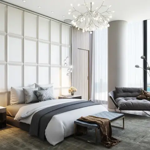 Render of a double-height bedroom where a full-wall grid of upholstered panels backs the bed, a firefly-bulb chandelier hangs centre