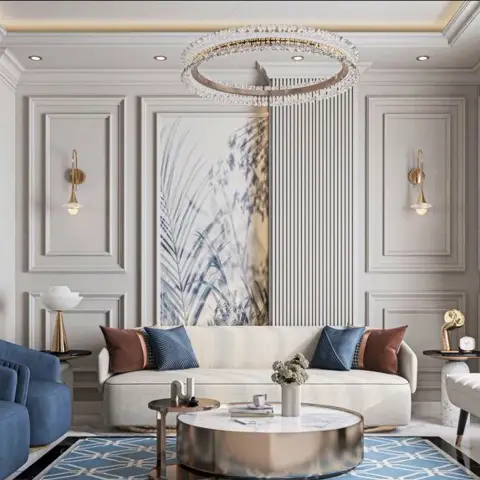 Render of a grey panelled living room with a crystal ring chandelier over a curved cream sofa, blue velvet tub chairs