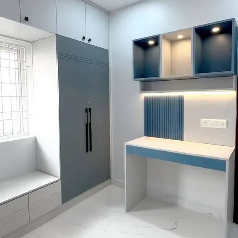 Render of a kids' study nook with a blue fluted panel above a white-and-blue study desk, open display cubbies and a tall grey wardrobe beside a window seat.