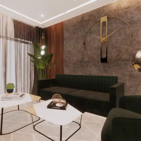 Render of a living room corner with two emerald channel-tufted sofas against a grey textured wall carrying an oversized open-frame gold clock
