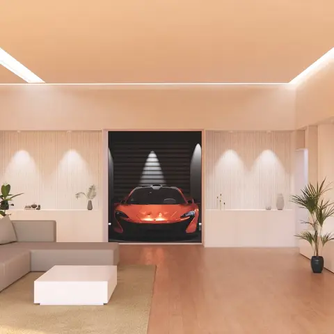 Render of a living room with an L-shaped sectional sofa and a floating TV console, opening onto a spotlit display garage showcasing a sports car.