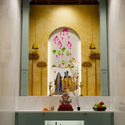 Render of a marble-framed pooja niche with a hand-painted Pichwai Shrinathji mural in an arched recess on gold-textured plaster