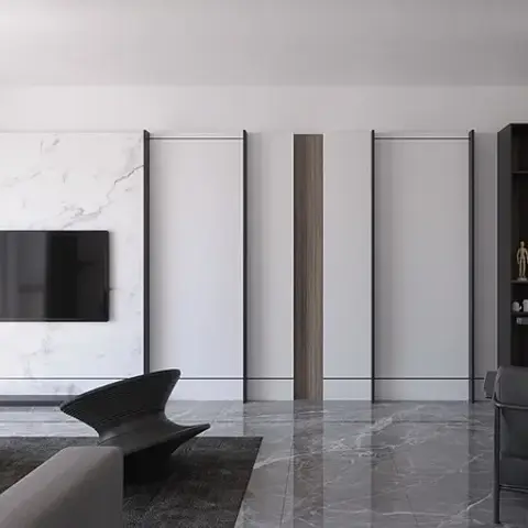 Render of a monochrome living room with a marble panel TV wall framed in black metal strips, a sculptural black lounge chair, a round stone coffee table