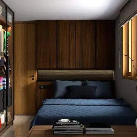Render of a tight bedroom built almost entirely in dark walnut — a low platform bed in navy linen under an overhead loft storage run with a concealed strip