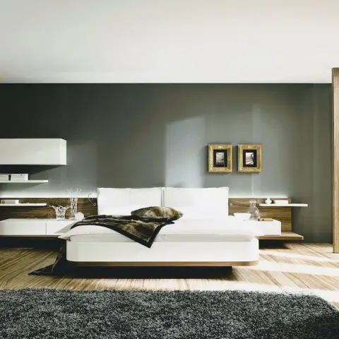 Render of a wide bedroom where a low white platform bed on a walnut plinth floats in front of a graphite feature wall