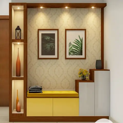 Render of an entryway unit with a yellow shoe cabinet topped by a buttoned seat pad, damask wallpaper inside a wood frame, two botanical prints